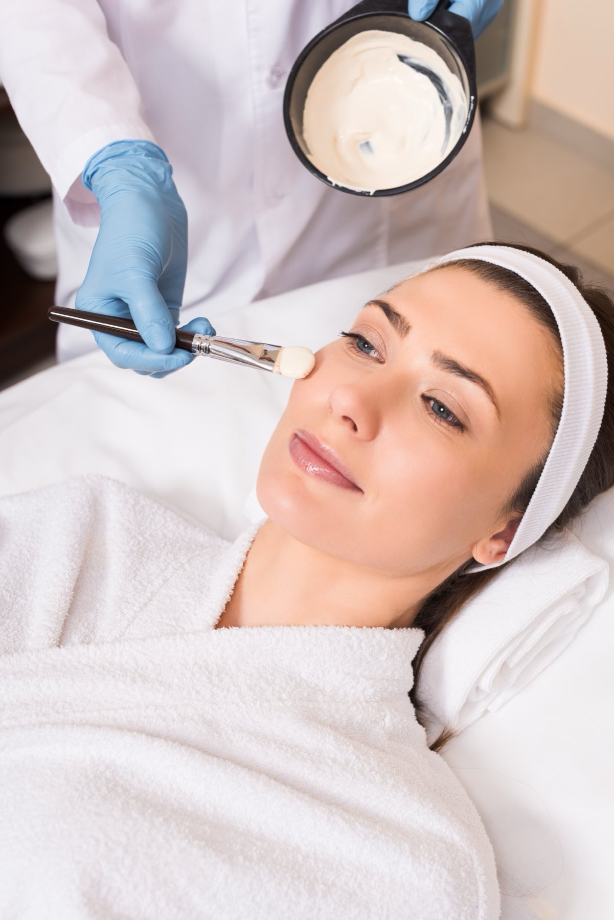 Woman receiving a professional cosmetic mask treatment in a clinical setting